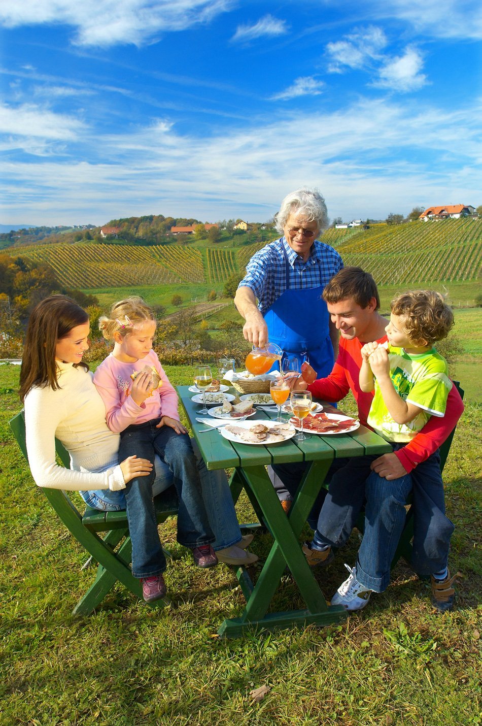 mlada družina za obloženo mizo zunaj ob lepem vremenu