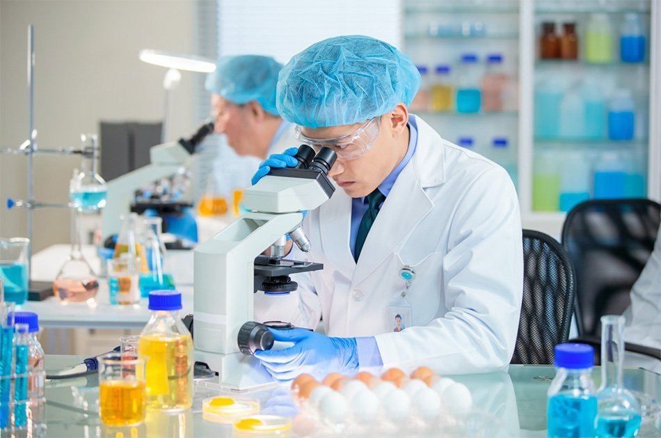 Laboratorijski tehnik opazuje skozi mikroskop